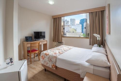 a hotel room with a bed and a desk and a window at Hotel Dan Inn São Paulo Higienópolis - METRÔ MACKENZIE in São Paulo