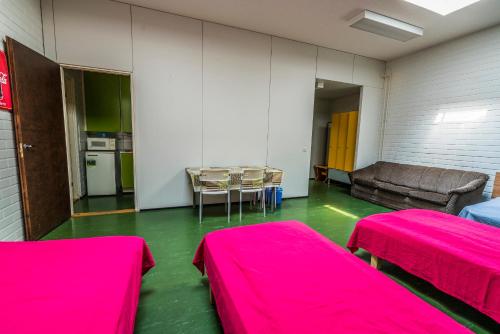 Habitación con 2 camas rosas y sofá en Minimotel, en Tohmajärvi