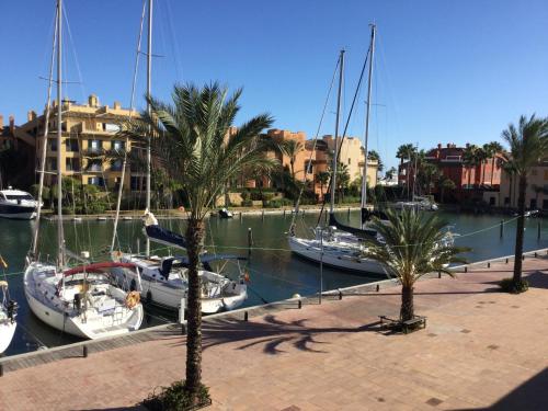 a group of boats docked in a marina with palm trees at Ribera del Marlin - Sotogrande in Sotogrande