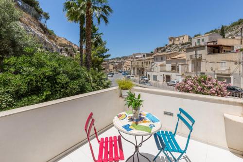 a table and chairs on a balcony with a view of a city at Scicli Albergo Diffuso in Scicli