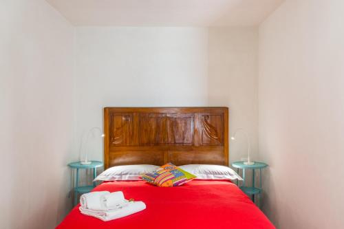 a bedroom with a red bed with two blue tables at Scicli Albergo Diffuso in Scicli