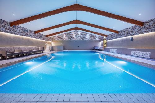 a large swimming pool with blue water in a building at Ashdown Park Hotel in Forest Row
