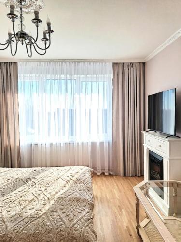 a bedroom with a bed and a tv and a window at White Home & Garden in Klaipėda