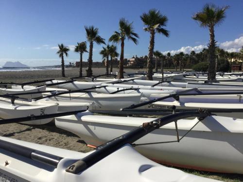 a row of boats lined up on a beach with palm trees at Ribera del Marlin - Sotogrande in Sotogrande