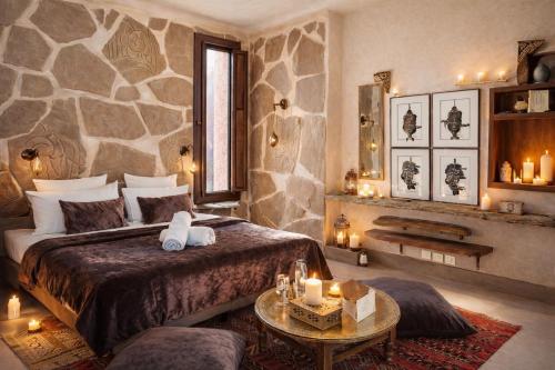 a bedroom with a large bed and a stone wall at Jnan Lotf Marrakech - Le Jardin de la Bienveillance in Marrakesh