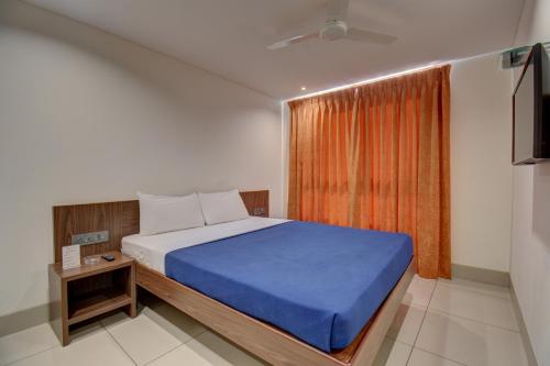 a bedroom with a bed with a blue blanket and a window at Hotel Dreamland in Pune
