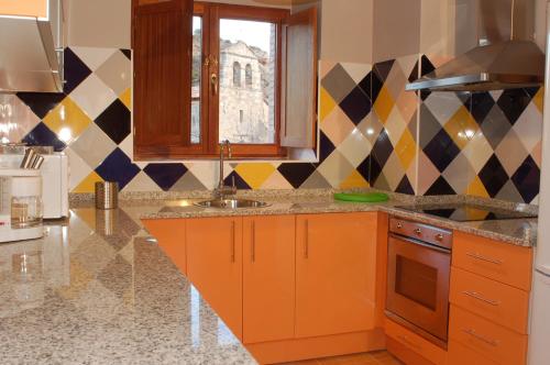 una cucina con armadi arancioni, lavandino e finestra di Casa Rural El Esquilador a Terminón