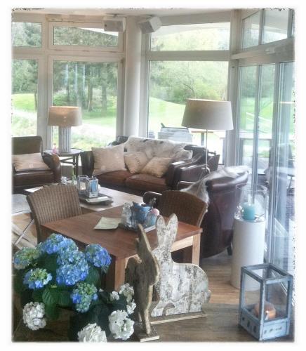 a living room with a couch and a table with flowers at Golfhotel Rheine Mesum in Rheine