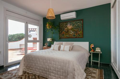 a bedroom with a white bed and a green wall at Villa Maravilla in Lloret de Mar