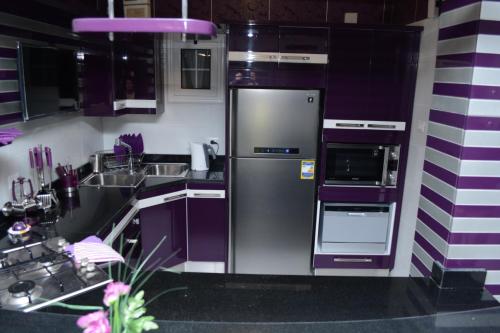 a kitchen with purple cabinets and a stainless steel refrigerator at Luxury Nile Maadi Cairo Apartment in Cairo