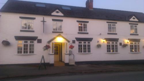 una casa blanca con una puerta amarilla y luces en The Railway Inn, en Forden