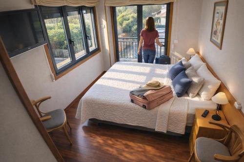 a woman standing in a bedroom with a bed with a suitcase at PENSION LUCERNA in Vigo