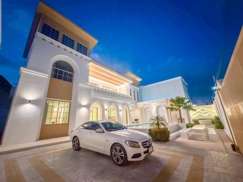 a white car parked in front of a house at Brown Empire Pool Villa Pattaya in Nong Prue