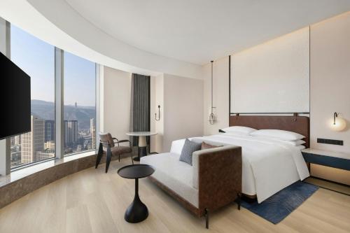 a hotel room with a bed and a chair at Four Points by Sheraton Tianshui in Tianshui