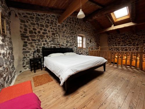 a bedroom with a large bed in a stone wall at Le Petit Moras in Chomérac