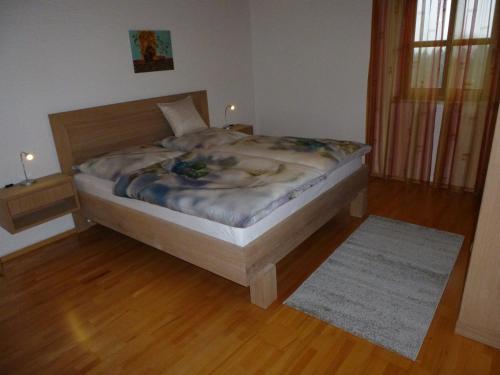 a bed in a bedroom with a wooden floor at Haus Annemarie in Philippsreut