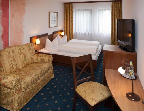 a hotel room with a bed and a couch at Sindersdorfer Hof in Hilpoltstein