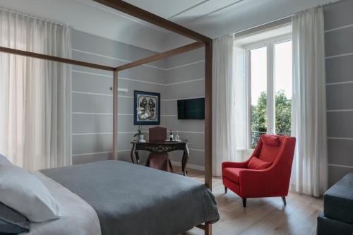 a bedroom with a bed and a red chair and a desk at Euterpe LHT in Agrigento