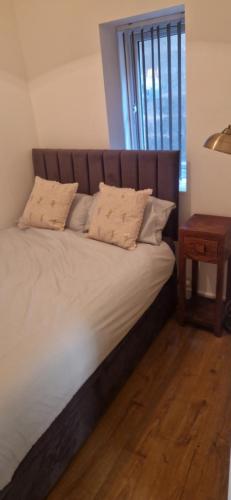 a bed with a wooden headboard and a side table at Penrith Centre Luxury 2 Bedroom Apartment with Parking in Penrith