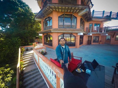 a man sitting on a couch in front of a house at Peaceful Cottage & Cafe Du Mont in Nagarkot