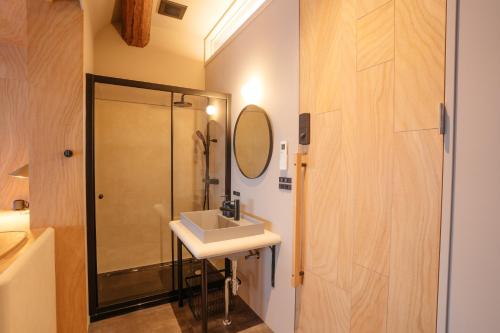 a bathroom with a shower and a sink and a mirror at APARTMENTS by Bed and Craft in Inami