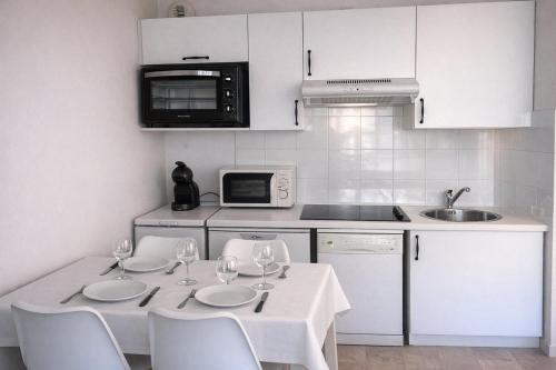 a kitchen with a table with chairs and a microwave at Cap des pins in Quend
