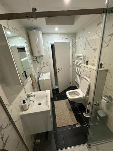 a white bathroom with a sink and a toilet at Čaršija Light Visoko in Visoko