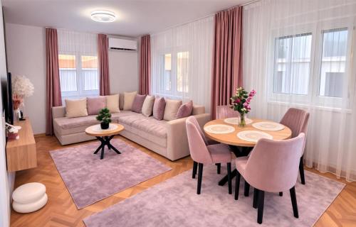 a living room with a couch and a table and chairs at Alma Apartment - Family Stay Across Aqua Park Raj in Vrnjačka Banja