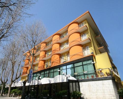 里米尼的住宿－蘇西酒店，街道上一座黄色和橙色的大建筑