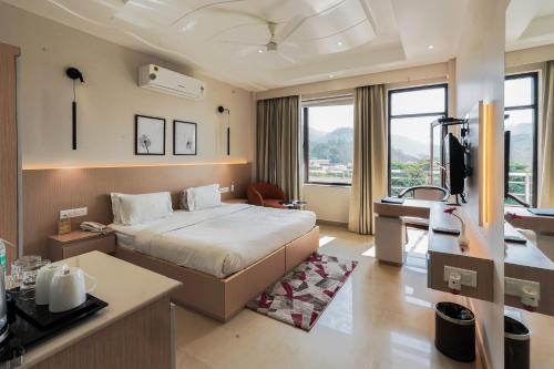a bedroom with a bed and a desk in a room at Hotel Yog Vashishth in Rishīkesh
