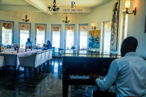 a man playing a piano in a restaurant at GINFORM at Hotel Petit Brussel in Lomé