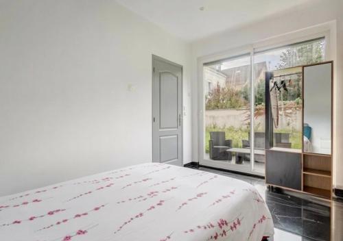 a white bedroom with a bed and a large window at Loft design climatisé in Thiais