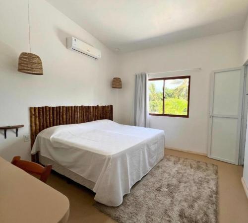 a bedroom with a white bed and a window at Casa levante in Paracuru