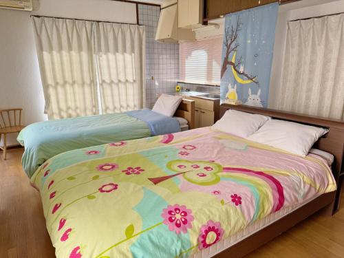 a bedroom with two beds with a hello kitty blanket at 別府ホーム in Beppu