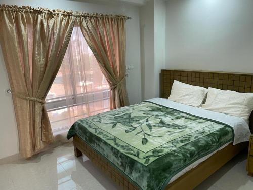 a bedroom with a bed and a window with curtains at Marine Tower in Rawalpindi