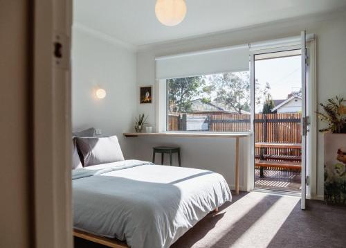 a bedroom with a bed and a large window at Kodok House in Melbourne
