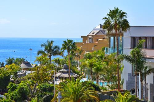 een uitzicht op een resort met palmbomen en de oceaan bij Adrián Hoteles Jardines de Nivaria in Adeje