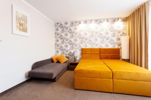 a hotel room with two beds and a couch at POKOJE APARTAMENTY ANASTAZJA in Grzybowo