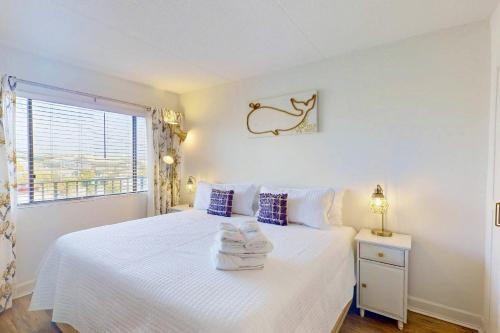 a bedroom with a bed with white sheets and a window at La Mare Vita in Carolina Beach