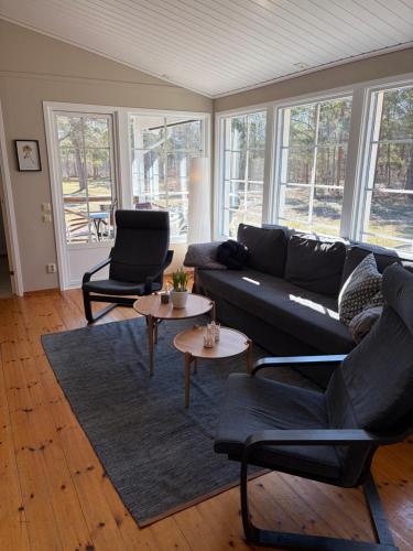 a living room with a black couch and two tables at Semesterhus nära Köpingsvik in Köpingsvik
