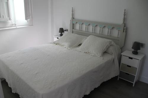 a bedroom with a white bed and a night stand at Apoteka apartaments in Figueres