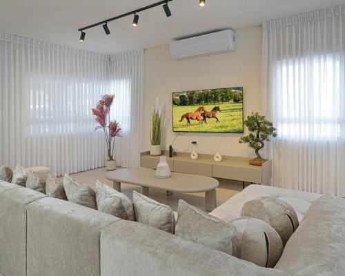 a white living room with a couch and a table at וילה ג'נסיס - וילה מהממת למשפחות עם בריכה פרטית מחוממת ליד הכנרת in Migdal