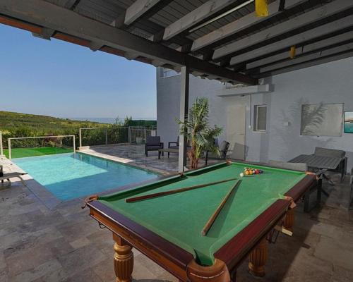 a pool table in front of a house with a swimming pool at וילה ג'נסיס - וילה מהממת למשפחות עם בריכה פרטית מחוממת ליד הכנרת in Migdal