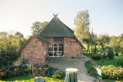 a barn with a thatched roof in a garden at Alter Hof am Elbdeich in Unbesandten