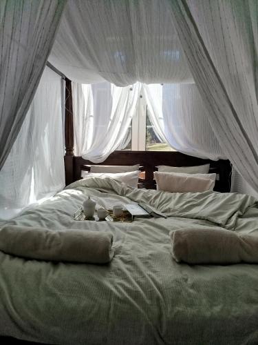 a large white bed with curtains and food on it at Ulęgałki Roztocze Stodoła in Jacnia