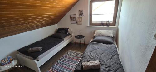 two beds in a small room with a window at Ferienwohnung mit Kreuzbergblick in Bischofsheim an der Rhön