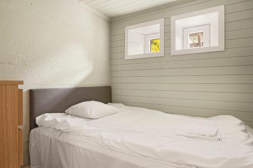 ein Bett mit weißen Laken und zwei Fenstern in einem Zimmer in der Unterkunft Trolltunga Basic in Tyssedal