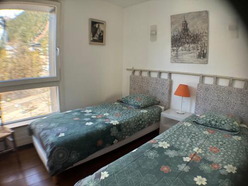 two beds in a small bedroom with a window at L'Outa Panoramique in Chamonix