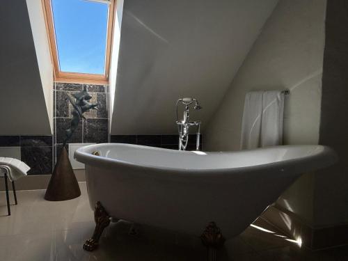 a white bath tub in a bathroom with a window at Kukšu muiža in Kukšas
