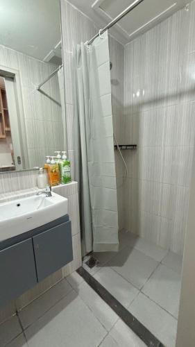 a white bathroom with a shower and a sink at Sorici Studio at Bella Tower in Surabaya